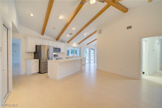 kitchen with light tile patterned floors, appliances with stainless steel finishes, high vaulted ceiling, white cabinets, and a kitchen island