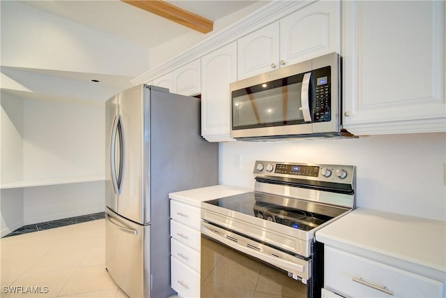 kitchen with beamed ceiling, light tile patterned flooring, white cabinets, and appliances with stainless steel finishes