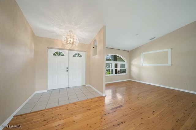 foyer entrance with lofted ceiling, a chandelier, and light hardwood / wood-style flooring