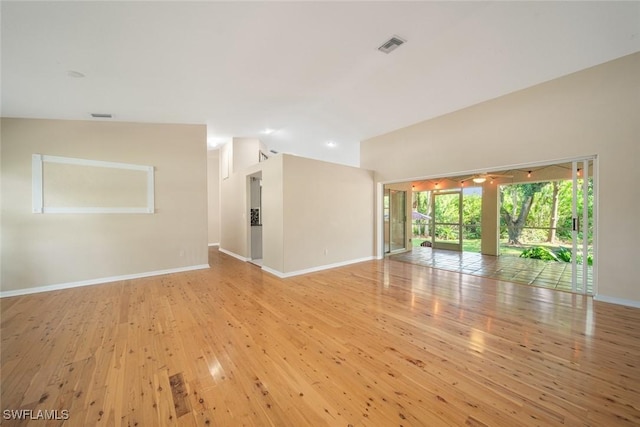 empty room featuring light wood-type flooring and vaulted ceiling