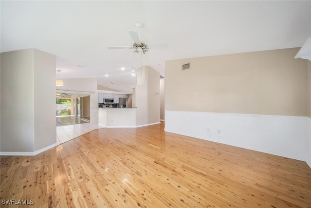 unfurnished living room featuring ceiling fan, light wood-type flooring, and vaulted ceiling