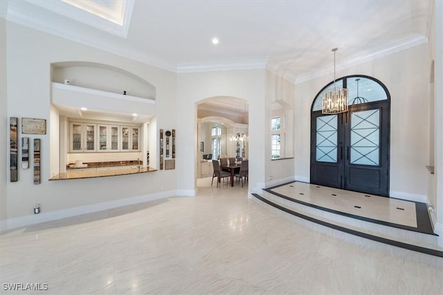 foyer entrance with a chandelier and crown molding