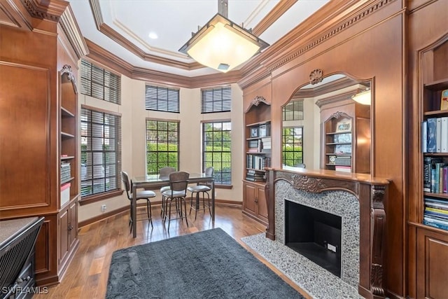 sitting room with light hardwood / wood-style floors, built in shelves, a high end fireplace, and ornamental molding