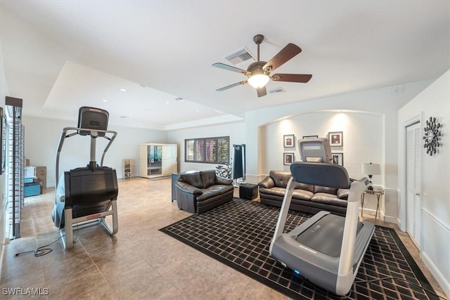 exercise room featuring ceiling fan and a tray ceiling