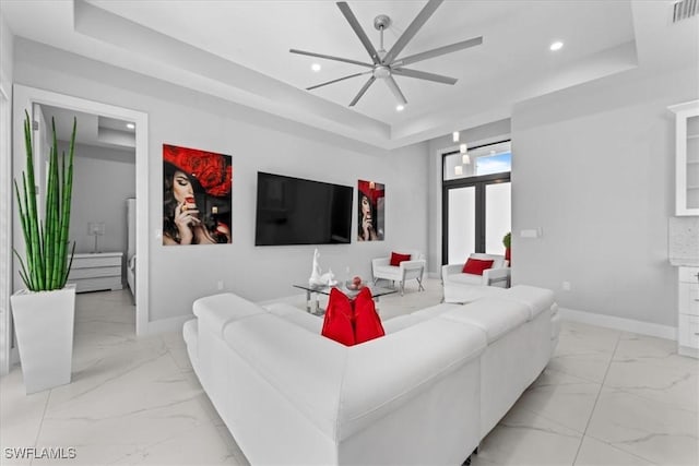 living room with ceiling fan and a tray ceiling