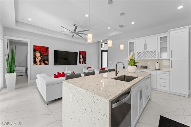 kitchen featuring sink, white cabinetry, dishwasher, pendant lighting, and a kitchen island with sink