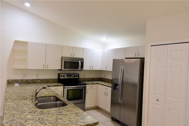 kitchen with vaulted ceiling, sink, light tile patterned floors, light stone counters, and stainless steel appliances