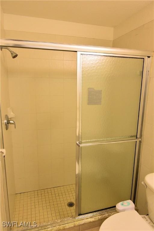 bathroom featuring a shower with shower door and toilet