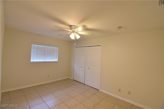 unfurnished bedroom featuring ceiling fan, a closet, and light tile patterned floors