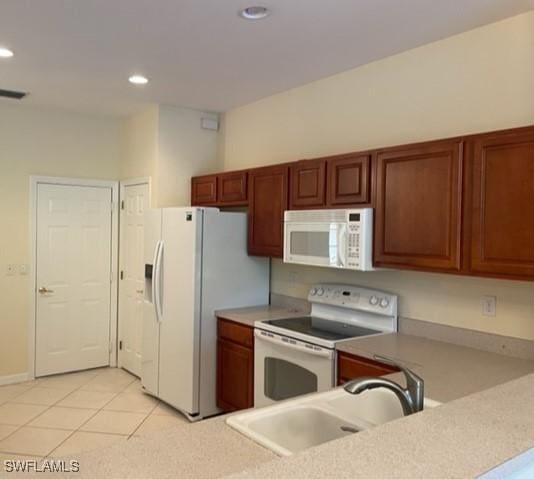 kitchen with sink, white appliances, and light tile patterned flooring