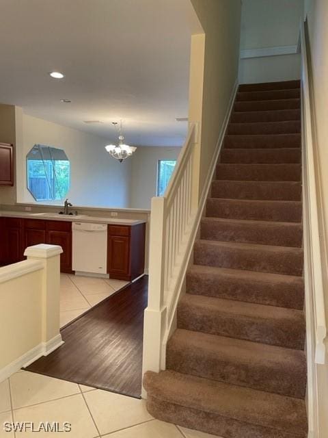 stairway with tile patterned flooring, sink, a wealth of natural light, and an inviting chandelier