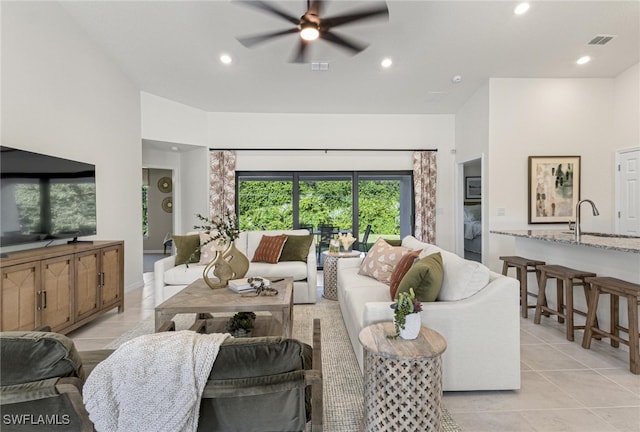 living room with sink, light tile patterned floors, and ceiling fan