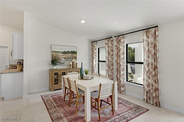 tiled dining area with a healthy amount of sunlight, a textured ceiling, and lofted ceiling