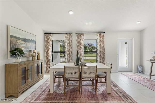 tiled dining area with a textured ceiling and a healthy amount of sunlight