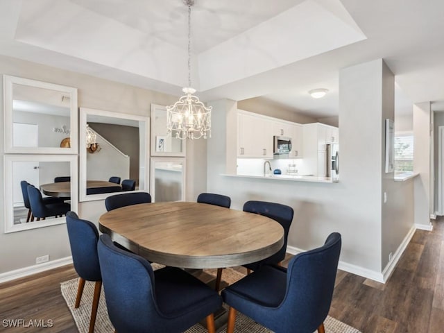 dining room featuring a notable chandelier, dark hardwood / wood-style flooring, and a tray ceiling