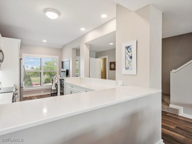 kitchen featuring dark wood-type flooring, appliances with stainless steel finishes, and kitchen peninsula