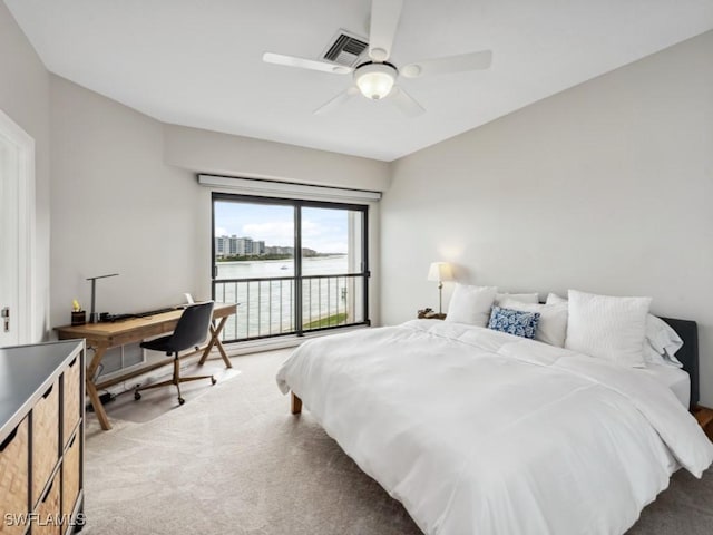 carpeted bedroom featuring a water view and ceiling fan