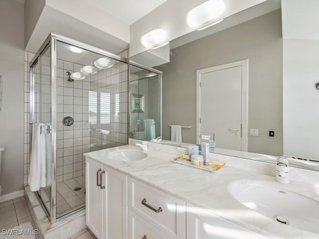 bathroom with a shower with door, vanity, and tile patterned floors