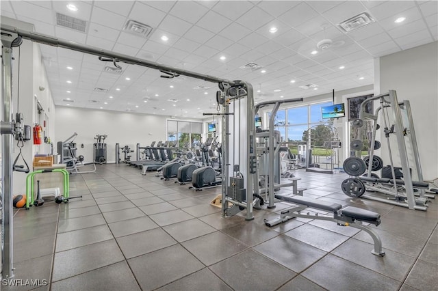 exercise room with a healthy amount of sunlight and a drop ceiling