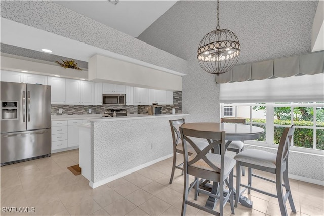 kitchen featuring appliances with stainless steel finishes, tasteful backsplash, a notable chandelier, decorative light fixtures, and white cabinets