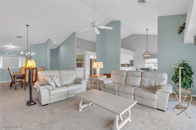 carpeted living room featuring ceiling fan with notable chandelier and high vaulted ceiling