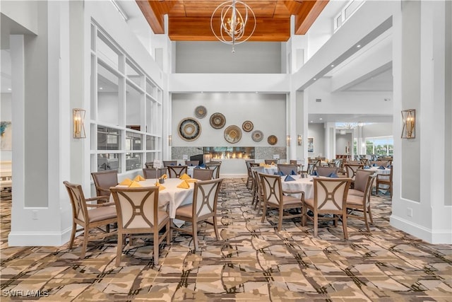 dining area featuring wood ceiling, a high ceiling, and a notable chandelier