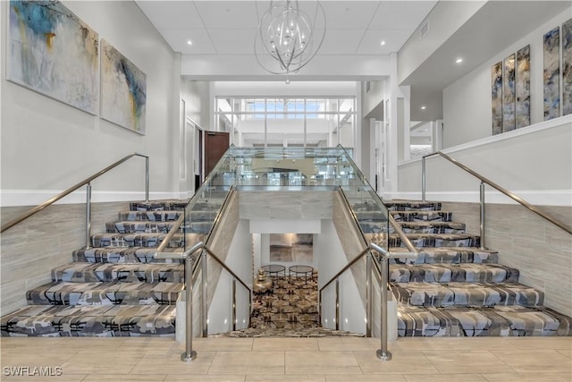 stairway featuring a notable chandelier and a towering ceiling