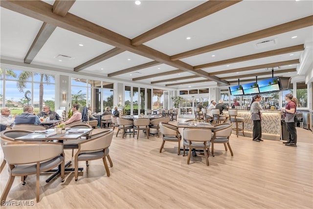 dining room featuring a wealth of natural light, light wood-type flooring, and beamed ceiling