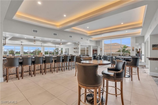 tiled dining space with a raised ceiling