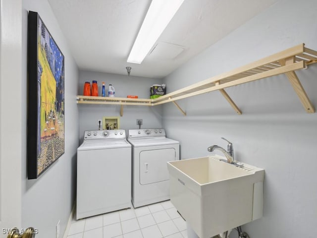 laundry area featuring light tile patterned flooring, washing machine and clothes dryer, and sink