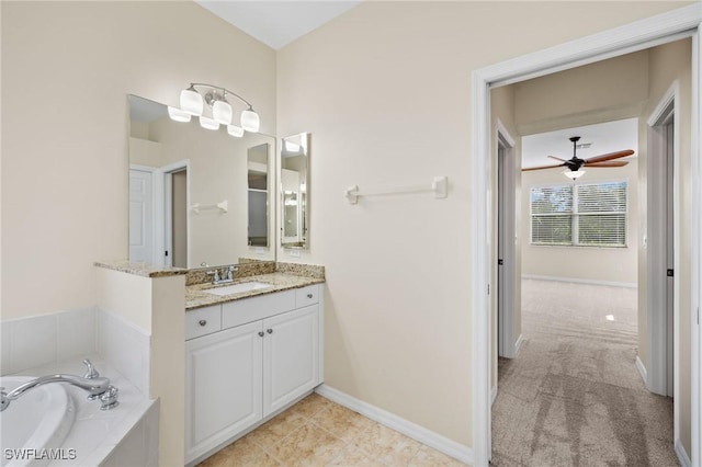 bathroom featuring ceiling fan, tiled tub, and vanity