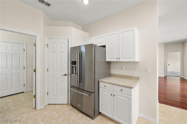 kitchen with white cabinets, light tile patterned flooring, and high end refrigerator