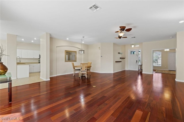 unfurnished living room with dark wood-type flooring, sink, and ceiling fan