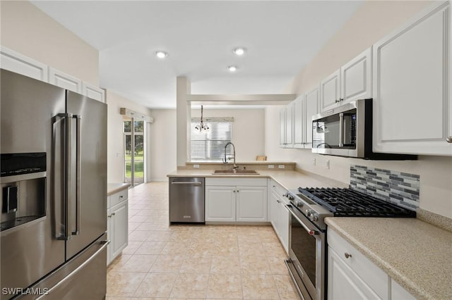 kitchen featuring pendant lighting, white cabinets, high end appliances, sink, and light tile patterned floors