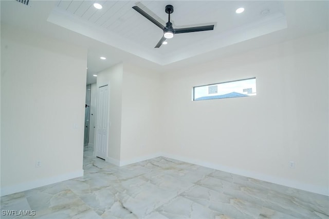 empty room featuring crown molding, ceiling fan, and a tray ceiling