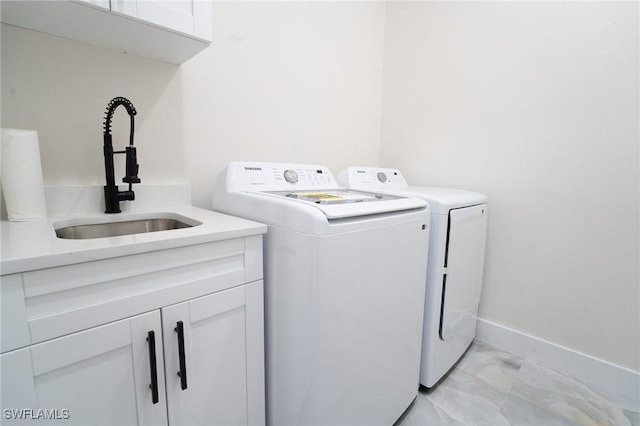 laundry room featuring cabinets, independent washer and dryer, and sink