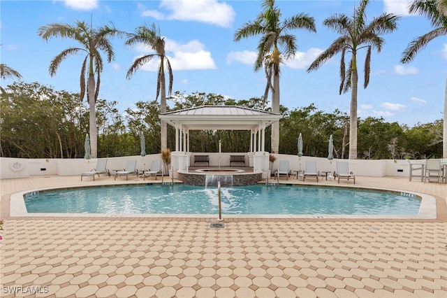 view of pool featuring a pool with connected hot tub, fence, a patio, and a gazebo