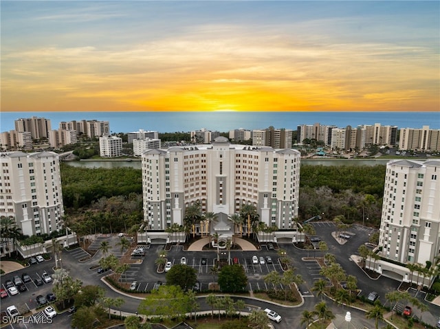 aerial view at dusk featuring a water view and a city view