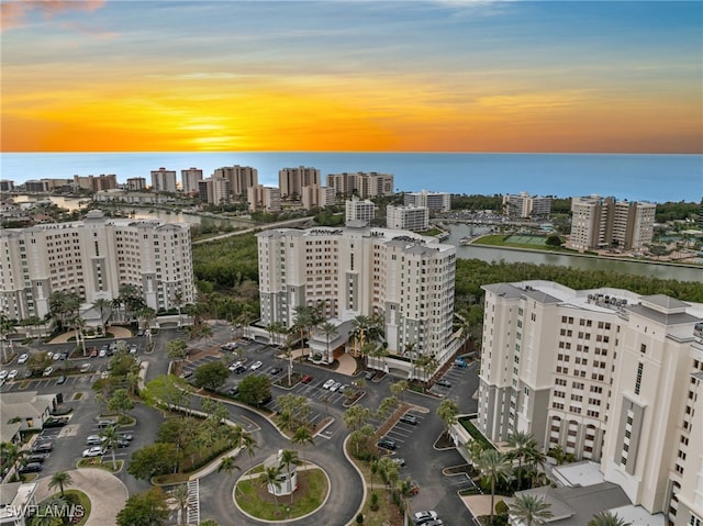 aerial view at dusk featuring a water view and a city view