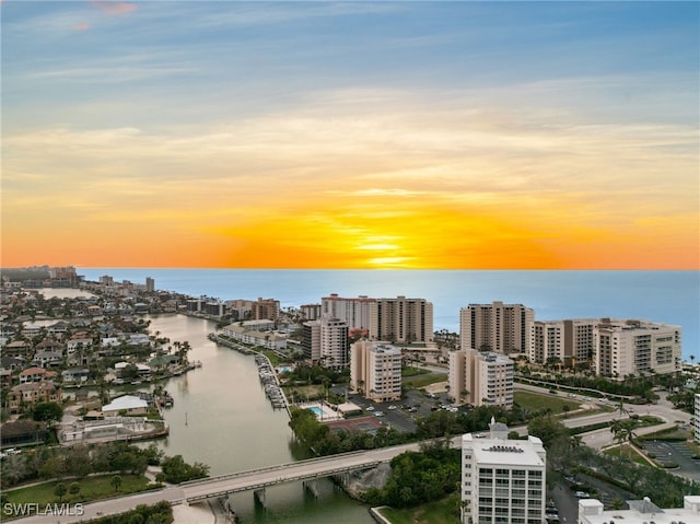 aerial view at dusk featuring a water view and a city view