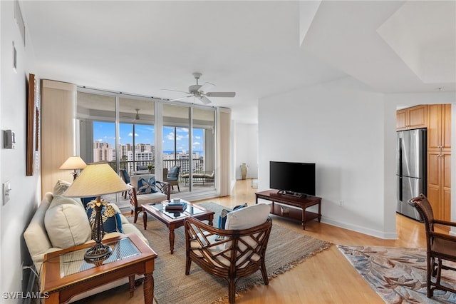 living room with baseboards, light wood-style floors, a ceiling fan, and floor to ceiling windows