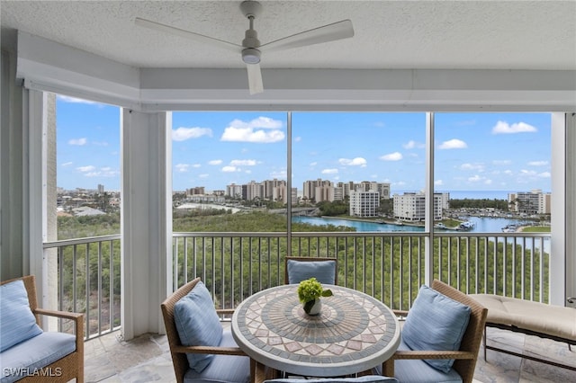 sunroom / solarium with a view of city, a water view, and a ceiling fan