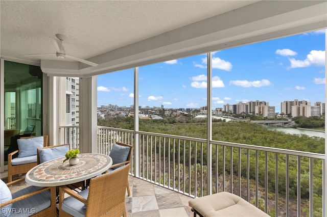 sunroom featuring a view of city and a water view