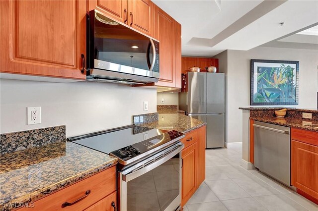 kitchen featuring dark stone countertops, light tile patterned floors, and appliances with stainless steel finishes