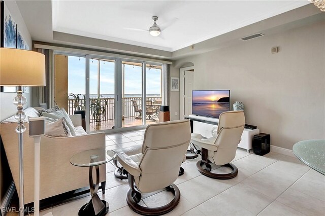 living room featuring ceiling fan, a raised ceiling, and light tile patterned floors