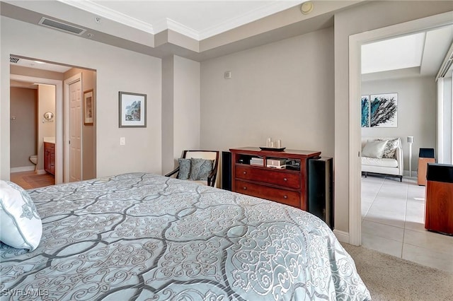 bedroom featuring light carpet, crown molding, and ensuite bath