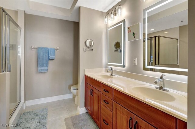 bathroom featuring tile patterned flooring, vanity, a shower with shower door, and toilet