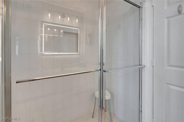 bathroom with a shower with shower door and tile walls