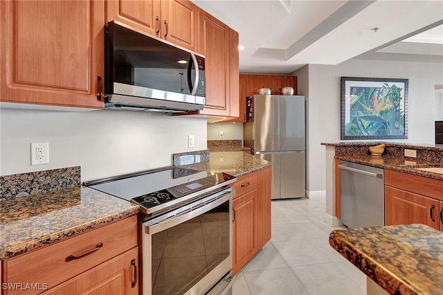 kitchen featuring light tile patterned floors, stainless steel appliances, and dark stone countertops