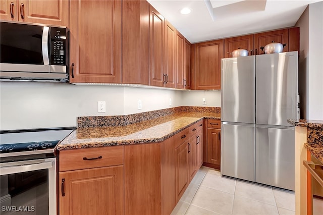 kitchen with appliances with stainless steel finishes, light tile patterned floors, and light stone counters